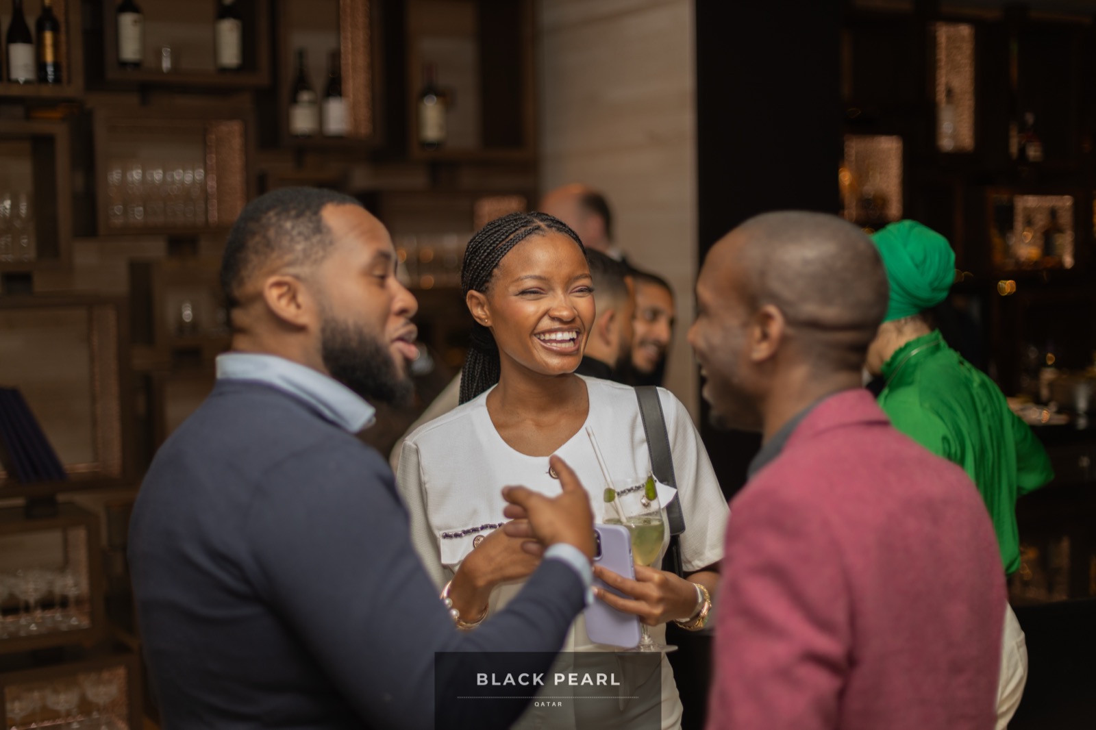 Three Black Pearl members laughing together in conversation at a bar