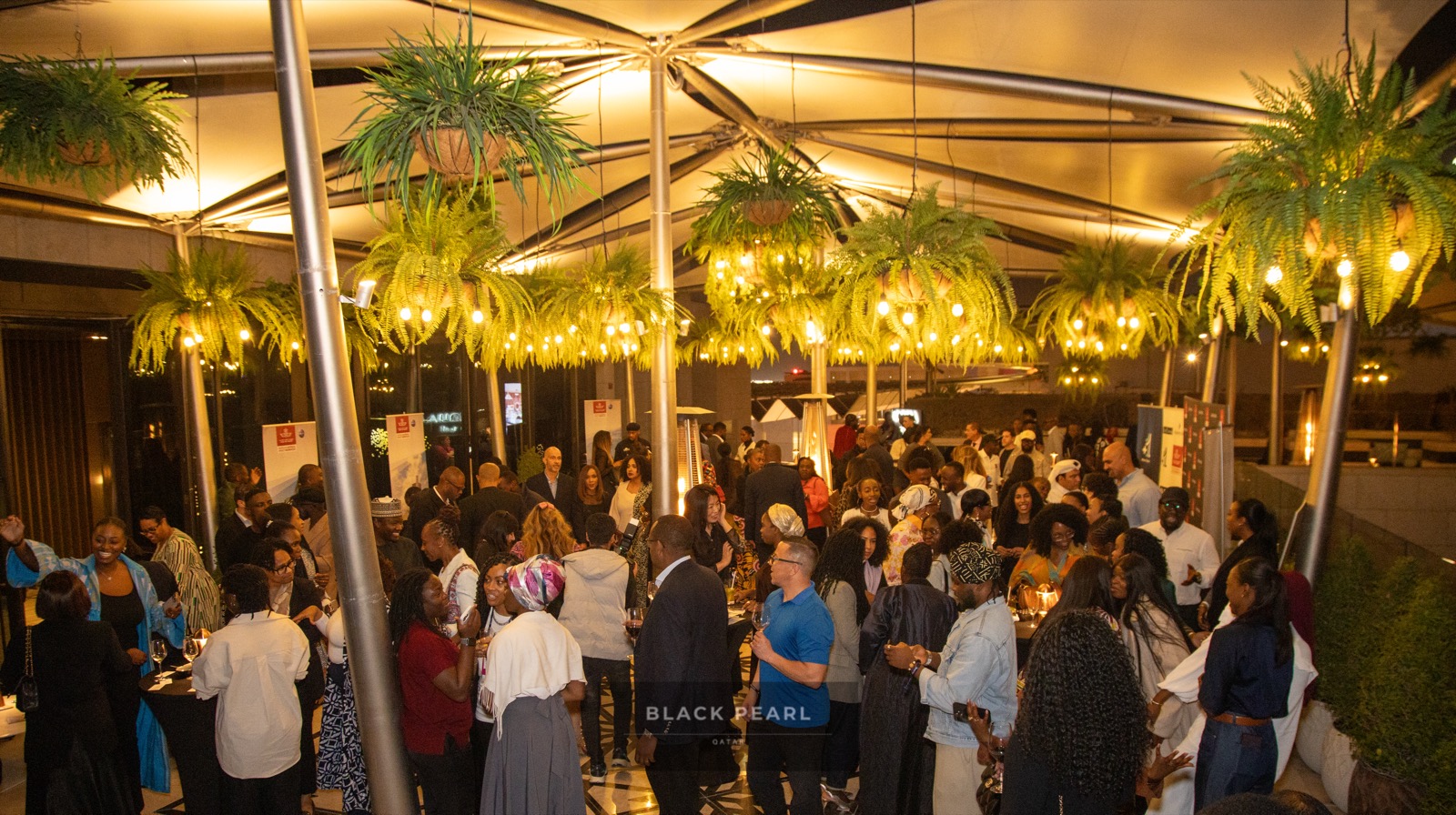 A crowd of Black Pearl members gathered together at an evening rooftop mixer